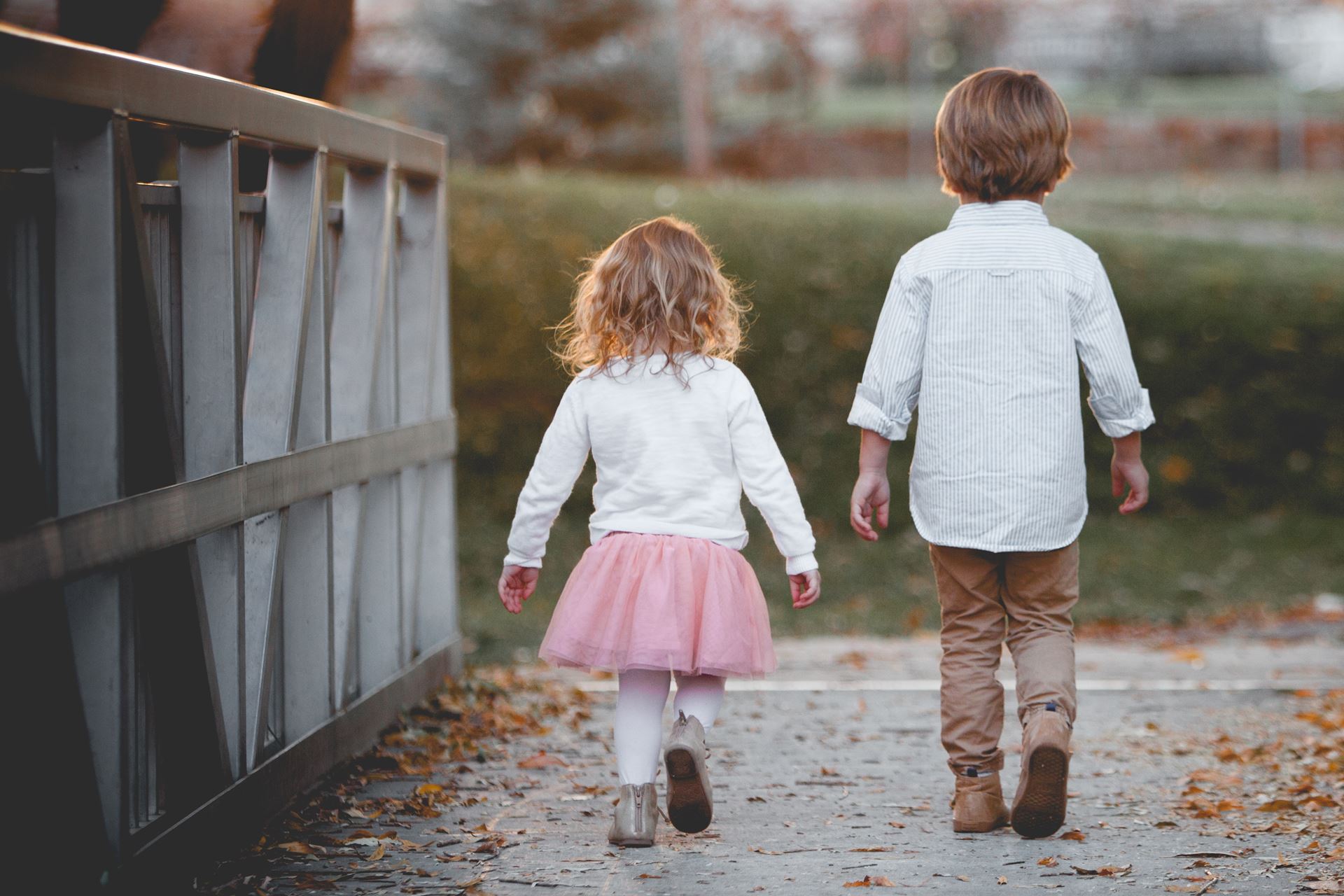 a little girl standing next to a fence